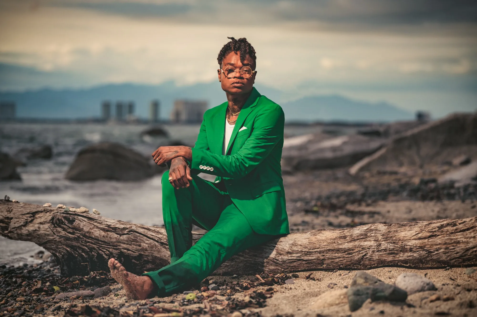 Portrait in a green suit on driftwood, Puerto Vallarta skyline behind